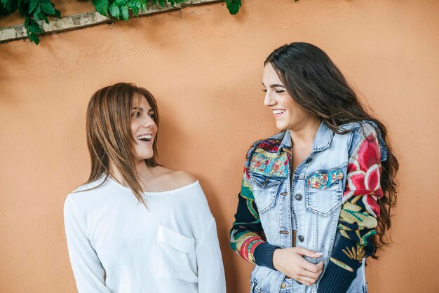 Two laughing friends in front of wall