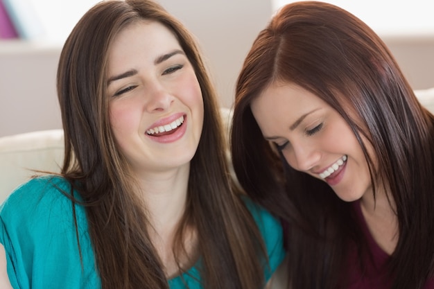 Two laughing friends sitting on the couch