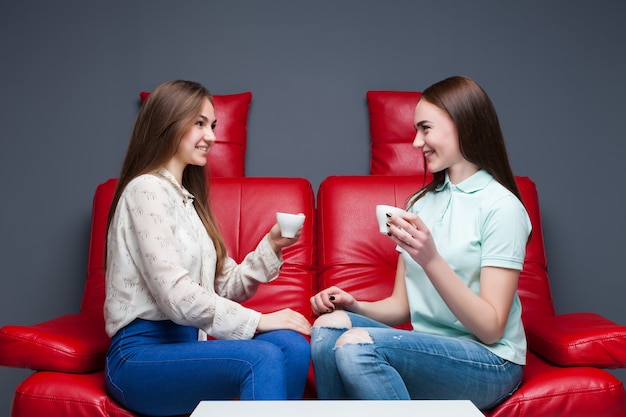 Two laughing girlfriends drinking coffee