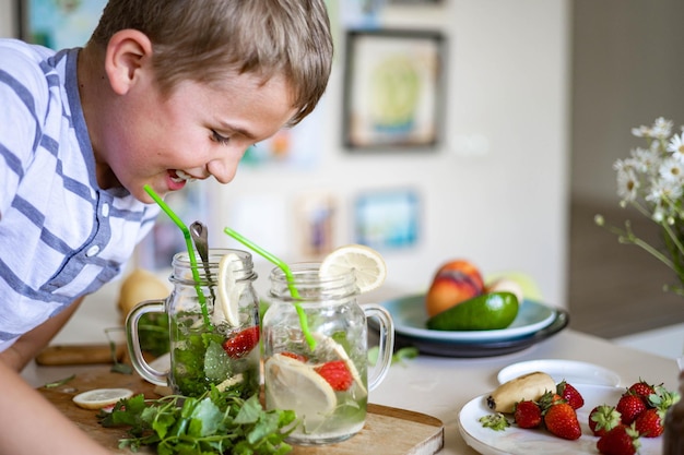 Two laughing little boys drinking refreshing vitamin summer cocktail from jar use straw having fun