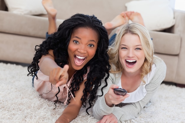 Two laughing women are lying on the ground and looking at the camera