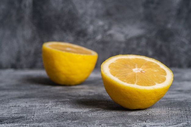 Two lemon slices, tropical citrus fruits on grey concrete table, angle view