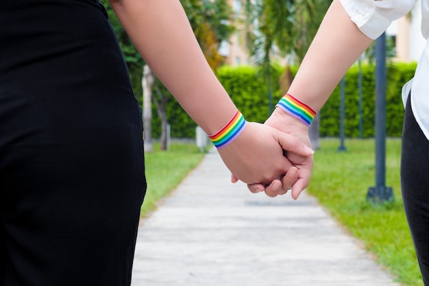 Foto due ragazze lesbiche che si tengono per mano indossando la bandiera dell'orgoglio