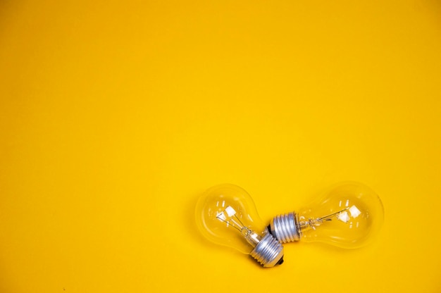 Two light bulbs placed on a yellow background