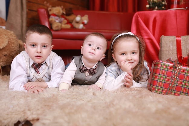 Due ragazzino e una ragazza si trovano vicino a una festa di capodanno dei regali dell'albero di natale. famiglia, felicità, vacanze, concetto di natale.