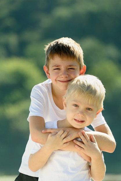 Two little boys are hugging outdoors