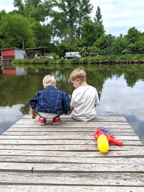 two little boys are sitting on the pier and playing with toys