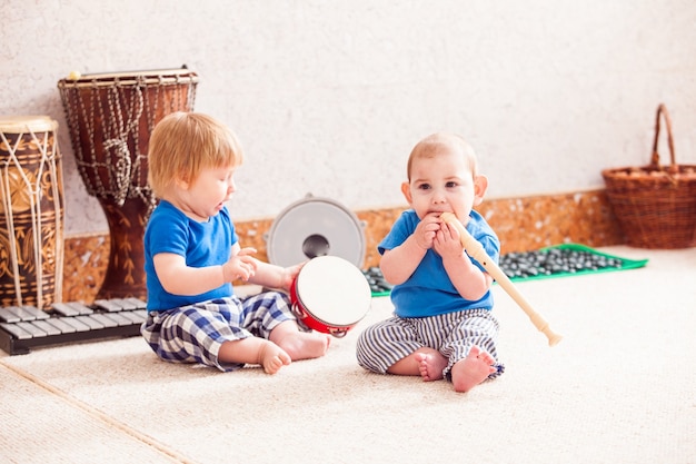 Two little boys enthusiastically playing with various musical instruments