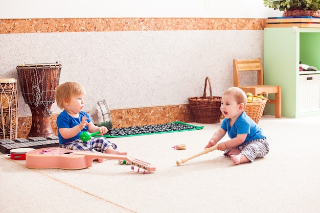 Два маленьких мальчика с энтузиазмом играют на различных музыкальных инструментах
