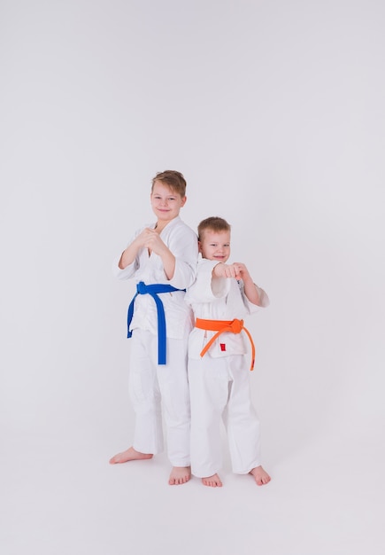 Two little boys in a white kimono stand in a pose on a white wall
