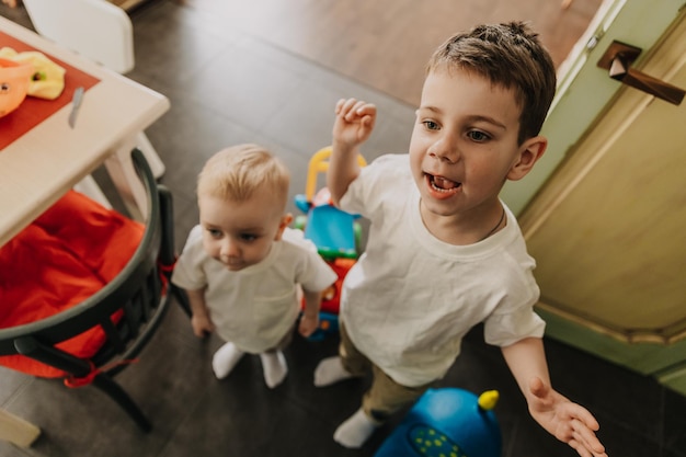 two little brothers playing at home running around the kitchen helping mom with cooking playing home