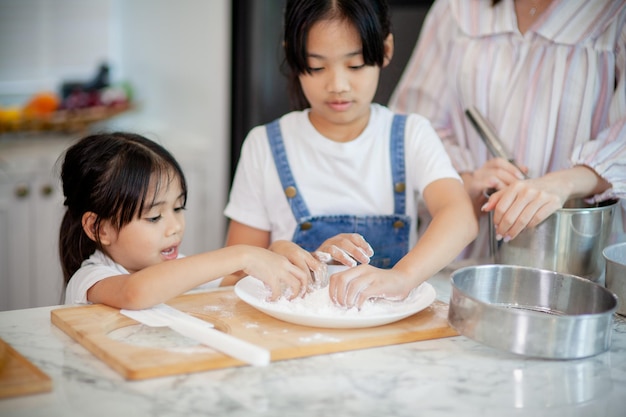 Two little cute Asian girls learning how to make bread and bakery with a curious and happy smile face She learns and plays