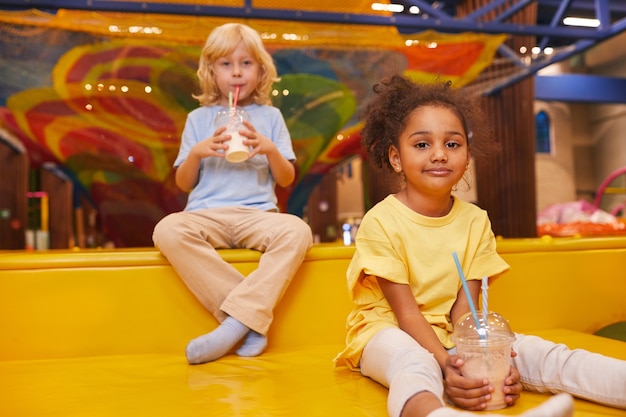 Two little friends drinking milk cocktails while resting after games in play center