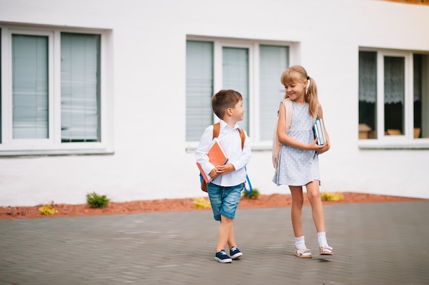 2人の小さな友達が学校に行きます。学童。学校に戻る