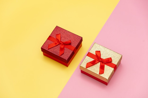 Two little gift boxes on pink and yellow backgrounds.