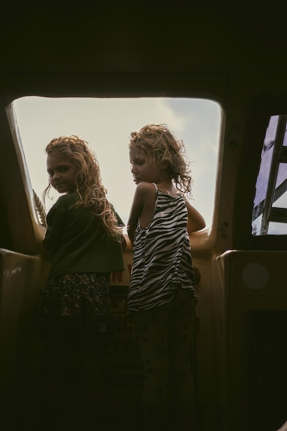 Two little girl friends travel on a boat, look out the open
window. children on a journey.