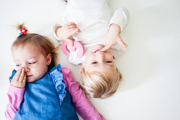 Two little girl lying togather on white background