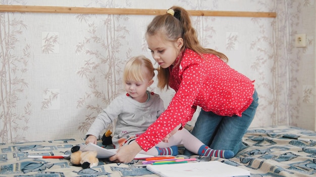 Two little girl sitting on the bed and drawing