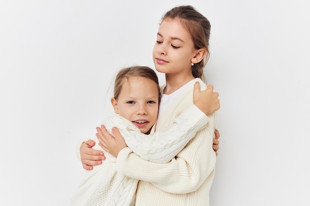 Two little girls baby clothes posing light background