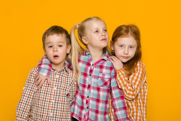 Two little girls and boy on yellow background