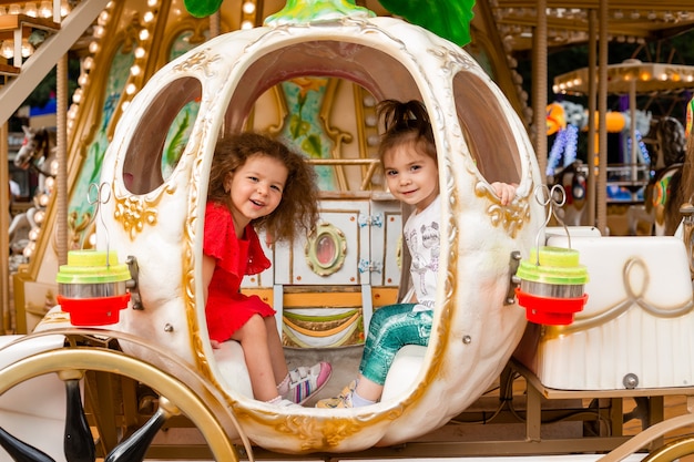 Two little girls in a carousel carriage. Cinderella princess girls in a carriage.