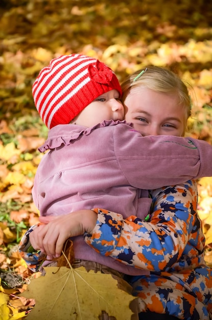 Two little girls embracing one another in the autumn park