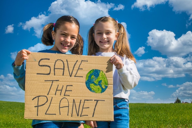 Foto due bambine in possesso di un cartello di cartone che dice salvare il pianeta.