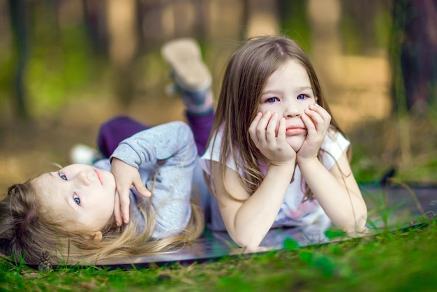 Two little girls lying on the grass in the park