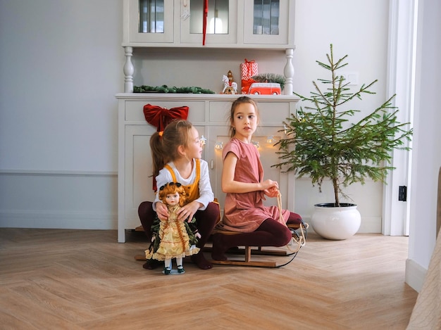 크리스마스 장식 으로 장식 된 고티나 에 있는 슬레드 에 앉아서 놀고 있는 두 명의 어린 소녀