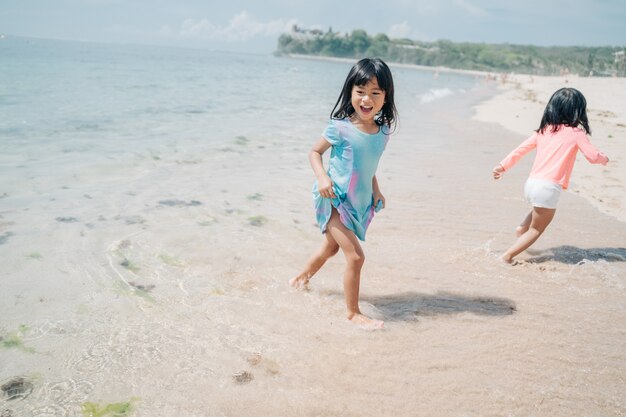 Two little girls playing chase in the beach