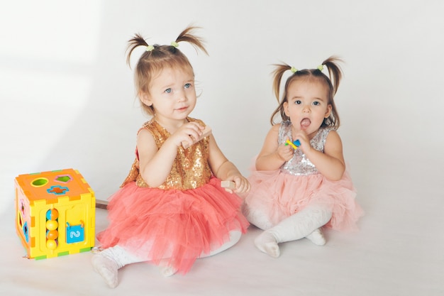 Two little girls playing on the floor on a white background