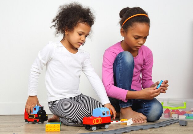 Две маленькие девочки играют в игрушечную железную дорогу