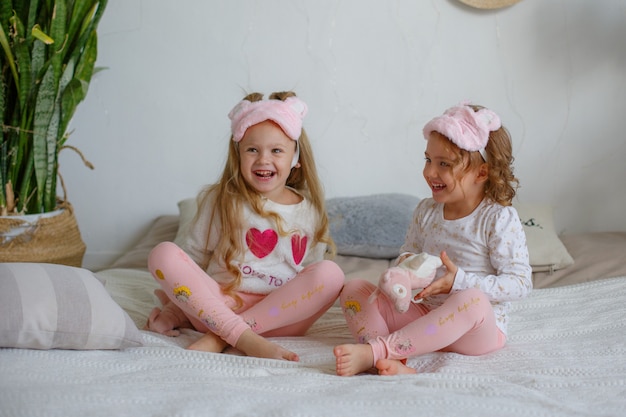 Two little girls in pyjamas sit on the bed and indulge