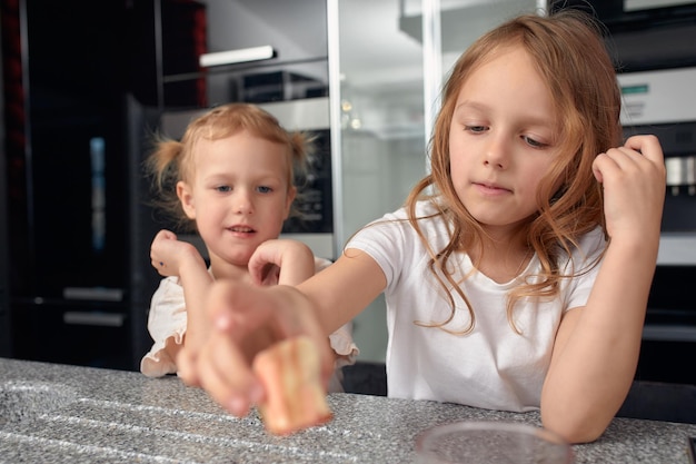 Two little girls siblings having fun and eating on the kitchen at home with japanese food