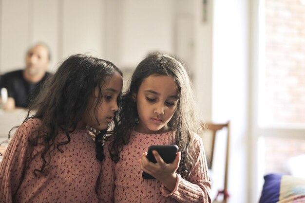 두 명의 어린 소녀 자매가 스마트폰을 본다