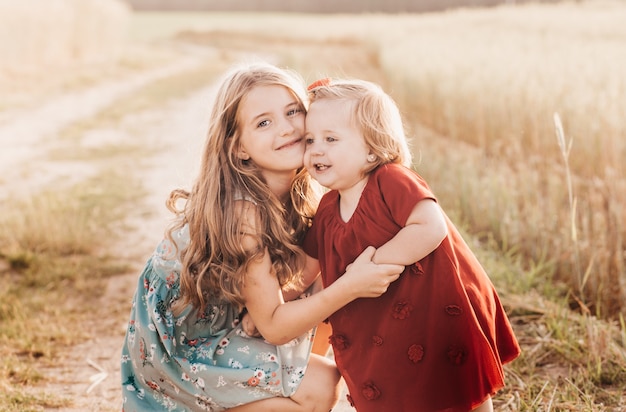 Two little girls sisters play in a wheat field