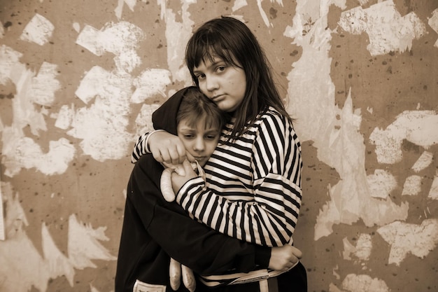 Two little girls standing in embrace at destroyed wall and\
afraid concept of latest news in world about russia\'s attack on\
ukraine