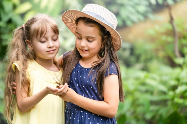 two little girls with butterflies in a greenhouse