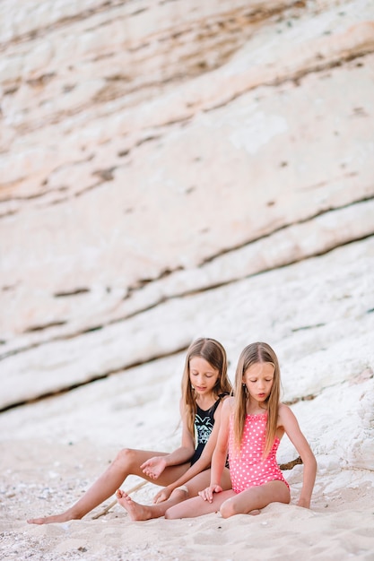 Two little happy girls have a lot of fun at tropical beach playing together