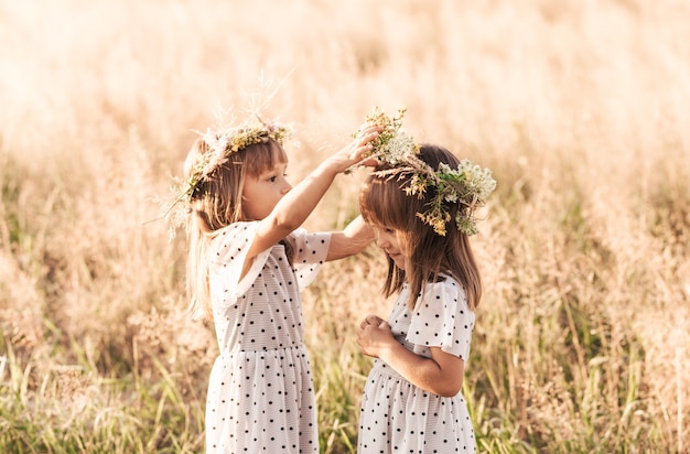 Due piccole gemelle identiche felici che giocano insieme in natura in estate. amicizia delle ragazze e concetto di gioventù. stile di vita attivo dei bambini.