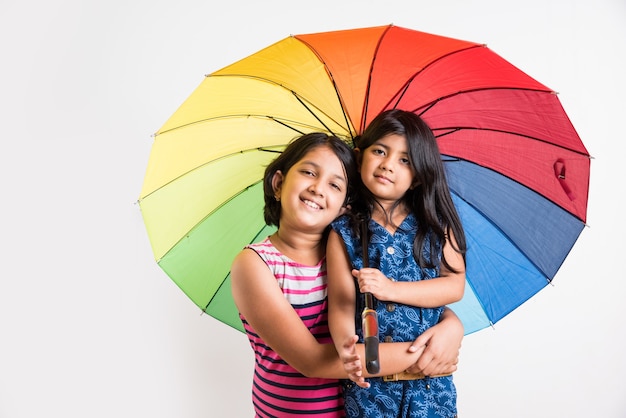 Due bambine indiane con ombrello colorato, isolate su bianco