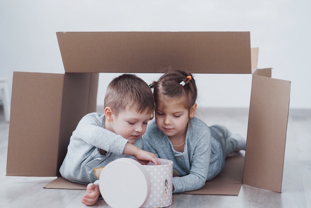 Two a little kids boy and girl playing in cardboard boxes. Concept photo. Children have fun