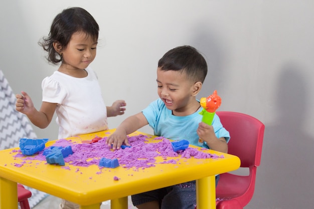 Two little kids play sand at home