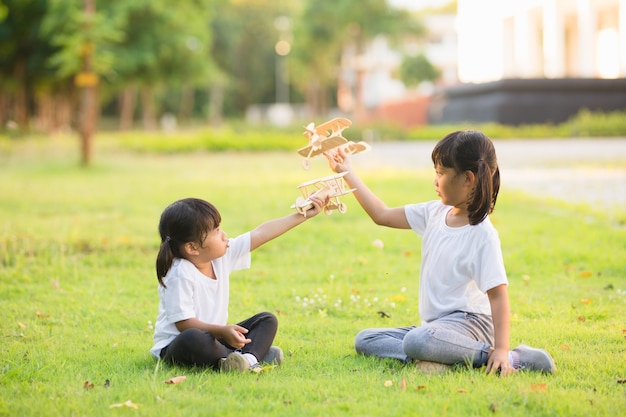 Due bambini piccoli che giocano con un aeroplano giocattolo di cartone nel parco durante il giorno