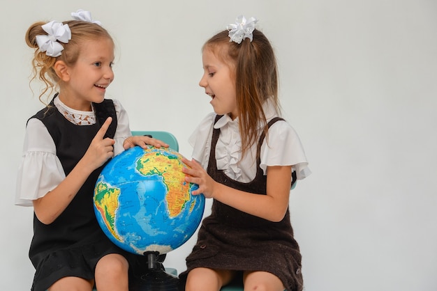 two little schoolgirls think in the classroom isolate