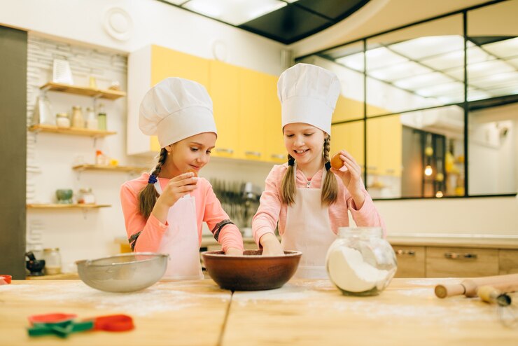 Photo two little sisters cooks in caps, cookies preparation on the kitchen. kids cooking pastry, children chefs makes dough, child preparing cake