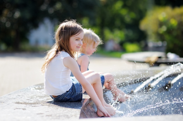 Two little sisters having fun in a city fountain 