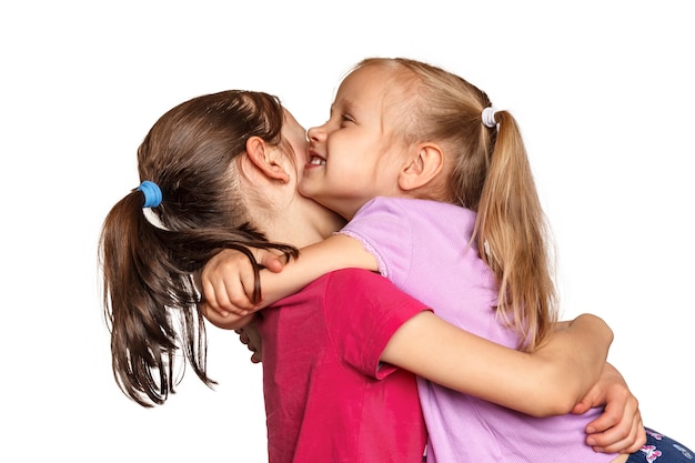 Two little sisters hugging on white background