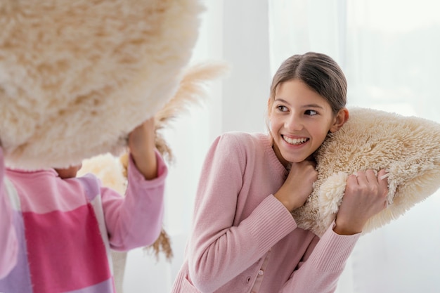 Two little sisters playing together at home with pillows