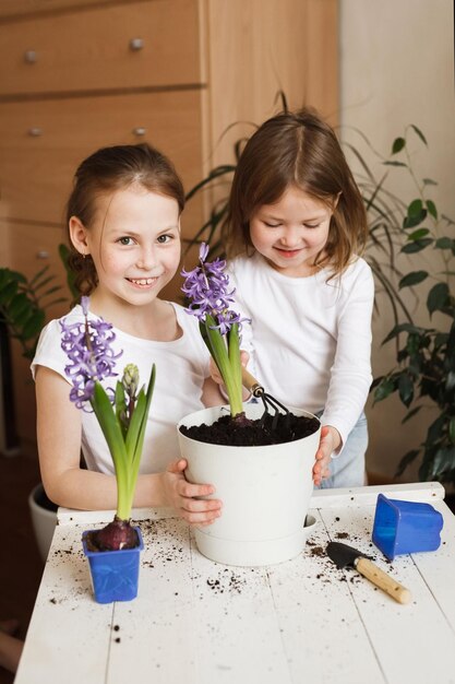 観葉植物のある部屋で自宅で咲く花を植え替える2人の妹